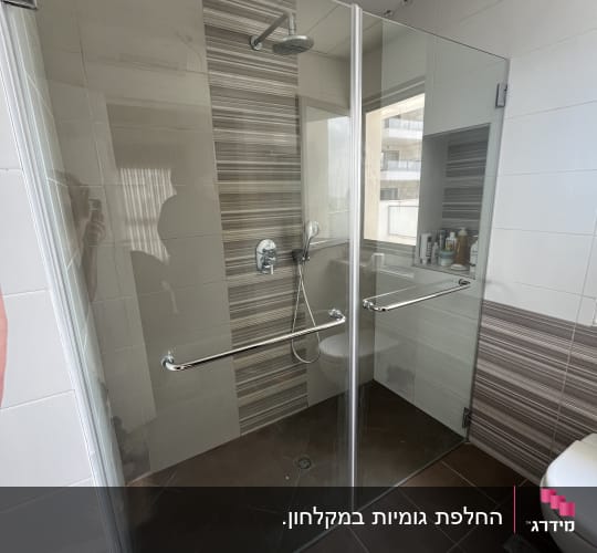 מקלחון זכוכית עם ראש מקלחת ומדף מוצרי טיפוח